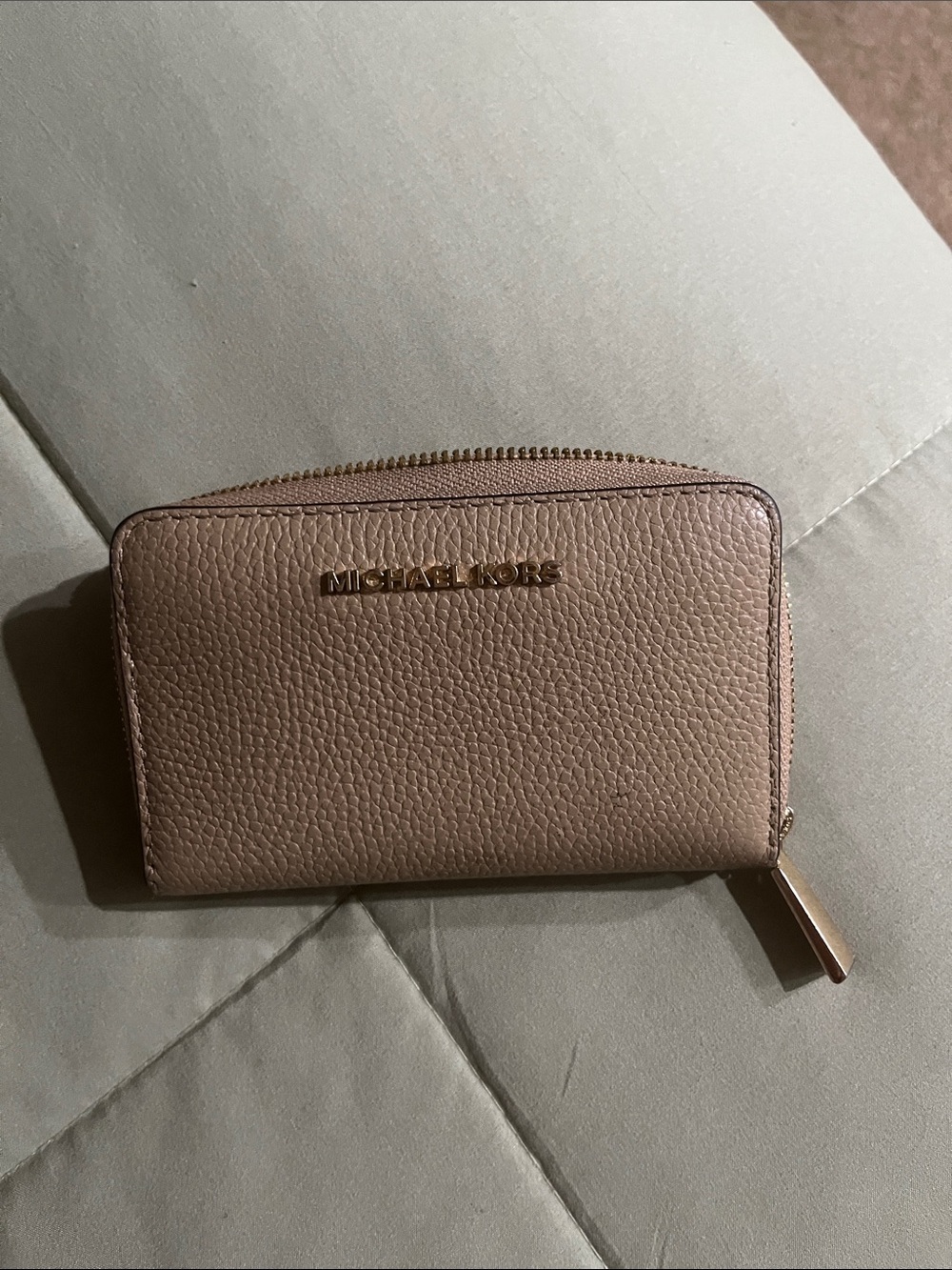 Michael Kors Pebbled Leather Zip Wallet in beige color.